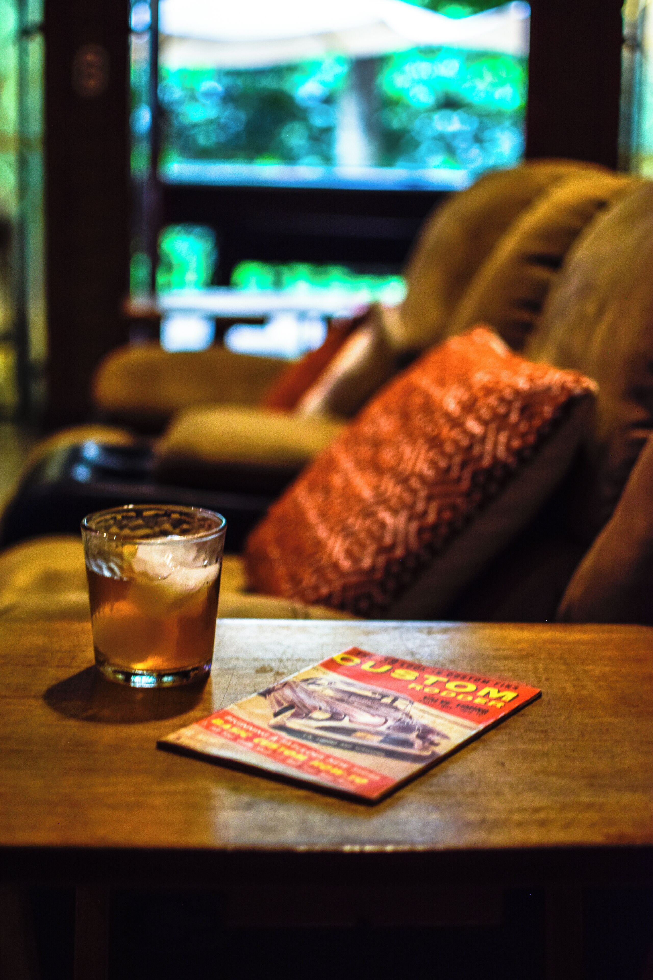 Un verre de bière sur une table en bois, avec un magazine à côté.