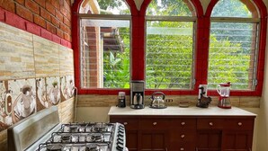 A kitchen with a gas stove, a coffee maker, and a blender on the counter.