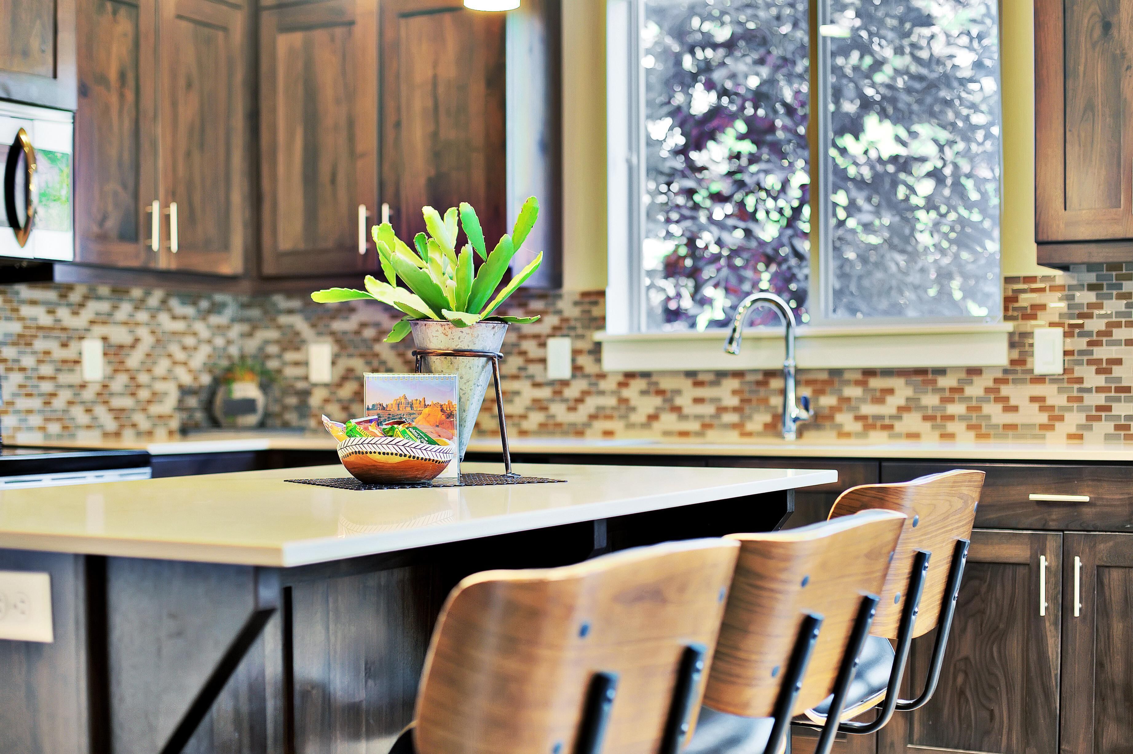 A kitchen with wooden cabinets, a tiled backsplash, and a window with a view of trees.