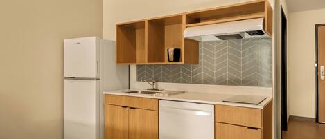 A compact kitchen with a refrigerator, dishwasher, and wooden cabinets.