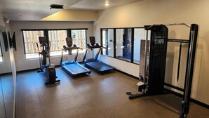 Un gimnasio con cintas de correr, máquinas de pesas y grandes ventanales.