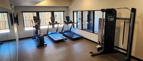 A gym with treadmills, a weight machine, and large windows.