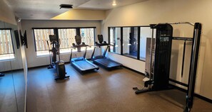 A gym with treadmills, a weight machine, and large windows. - LivAway Suites- Missoula (Missoula)