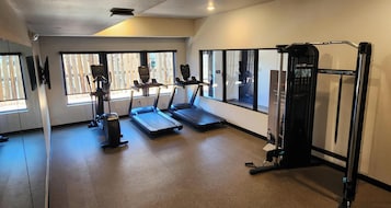 A gym with treadmills, a weight machine, and large windows.