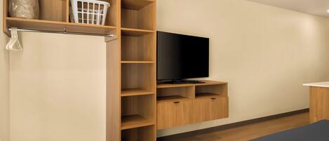 A modern room with a wooden shelving unit, a flat-screen TV, and a bed.