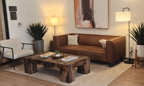 Ein möbliertes Wohnzimmer mit braunem Sofa, einem Holztisch, einem weißen Sessel und zwei Stehlampen.