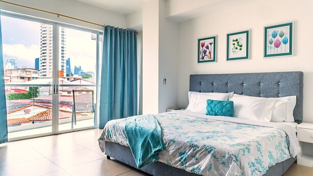 A modern bedroom with a large bed, a city view, and a balcony. - Apartment in San Francisco (Panama City)