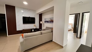 Una sala de estar moderna con un sofá grande, un televisor de pantalla plana montado en la pared y un diseño minimalista.