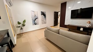 Una sala moderna con un sofá, un televisor de pantalla plana y arte abstracto en la pared.