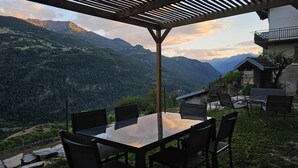 Mesa y sillas bajo una pérgola con vistas a la montaña.
