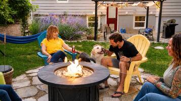 Une terrasse avec un foyer extérieur, des sièges et un espace jardin.