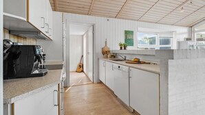 Eine moderne Küche mit weißen Schränken, einer Kaffeemaschine, einer Gitarre und einem Fenster mit Blick.