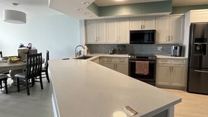 A modern kitchen with white cabinets, a large island, and stainless steel appliances.