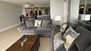 A modern living room with a grey sectional sofa, a wooden coffee table, and a ceiling fan.