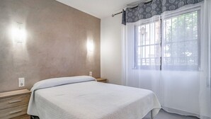 A bedroom with a bed, a nightstand, a wall socket, and a window with curtains. - 2 bedroom cozy apartment in Almunecar (Almunecar)