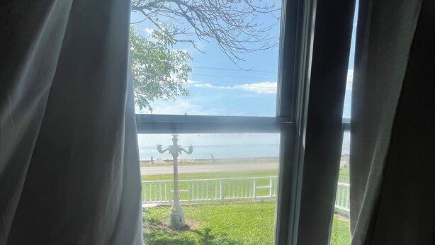 Vista a través de una ventana con un letrero que dice "BEACH" y una estatua al frente.