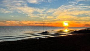 Una playa con un bote y aguas tranquilas durante el atardecer.