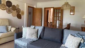 Ein Wohnzimmer mit grauem Sofa, beigem Sessel und einer Wand, die mit gewebten Körben dekoriert ist.