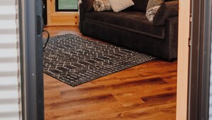 Une pièce avec un canapé marron, un tapis noir et blanc et un plancher en bois.