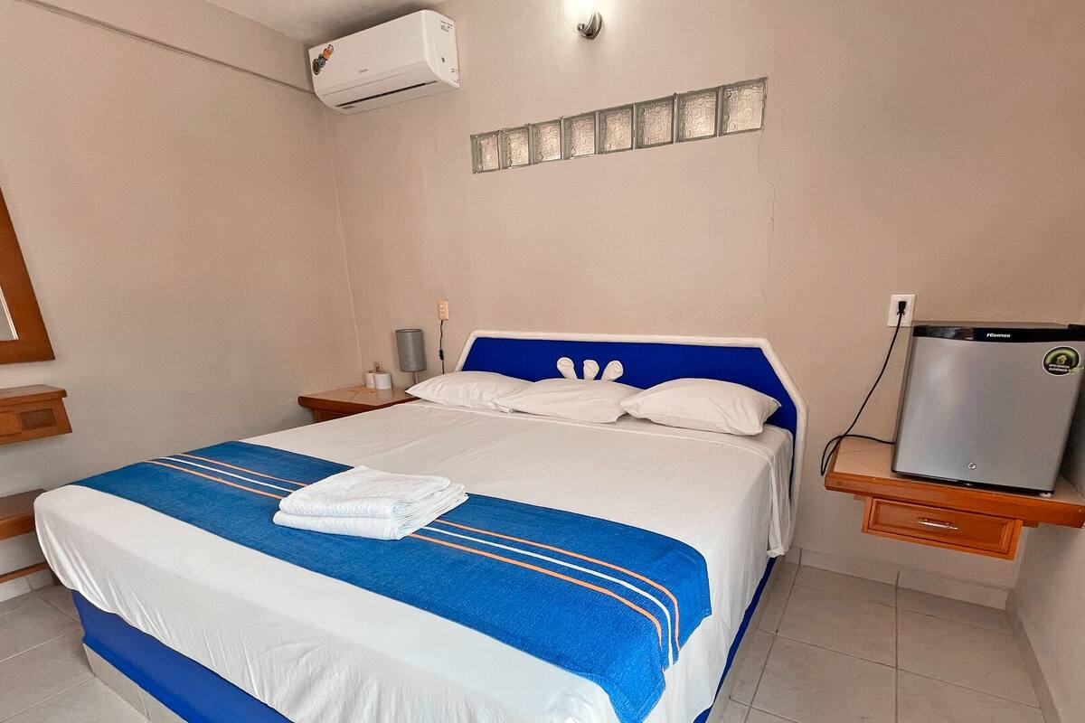 Una habitación de hotel con cama, televisor y aire acondicionado.