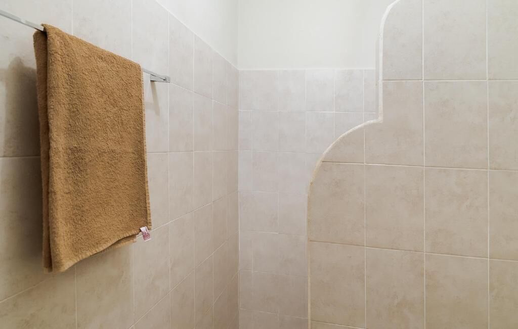 A bathroom with beige tiles, a towel hanging on a rack, and a shower area.