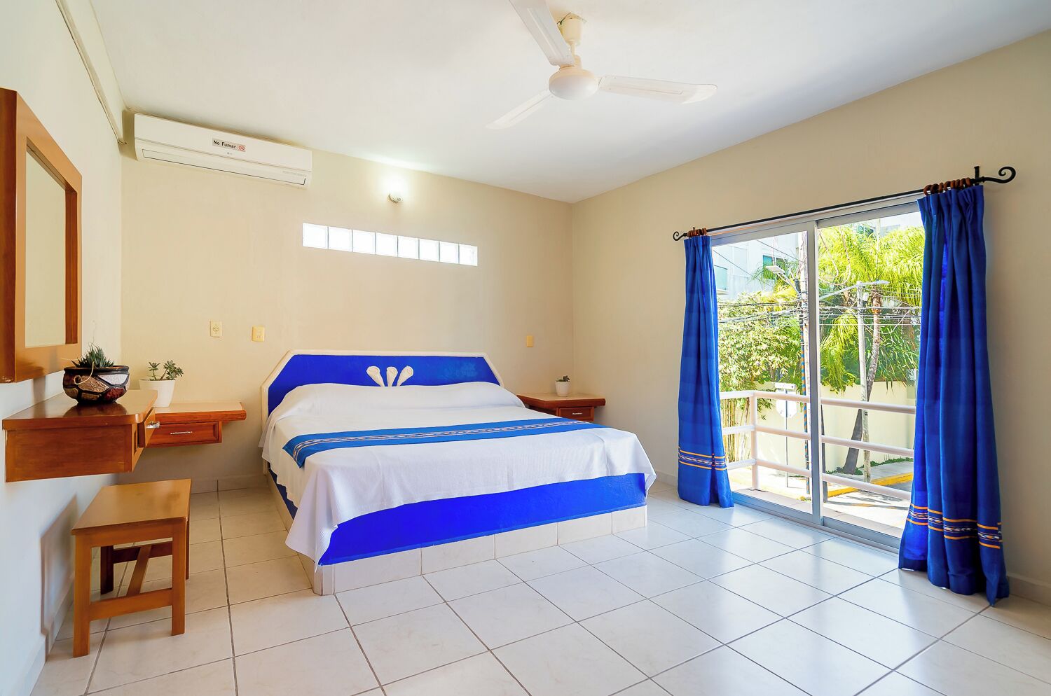 Un dormitorio con cama, escritorio, silla, ventana con cortinas y ventilador de techo.