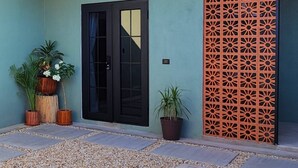 Un edificio moderno con una porta in vetro nero, piante in vaso e un pannello decorativo arancione.
