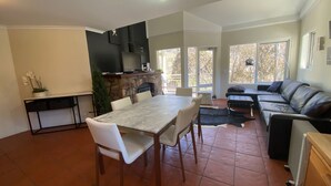 Un grand salon doté d’une cheminée en pierre, d’une table à manger avec des chaises, d’un canapé et d’un téléviseur.