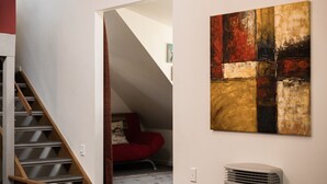 A staircase leading to a loft bedroom with a red chair and a large abstract painting on the wall. - Jagungal 2 - Thredbo (Thredbo)