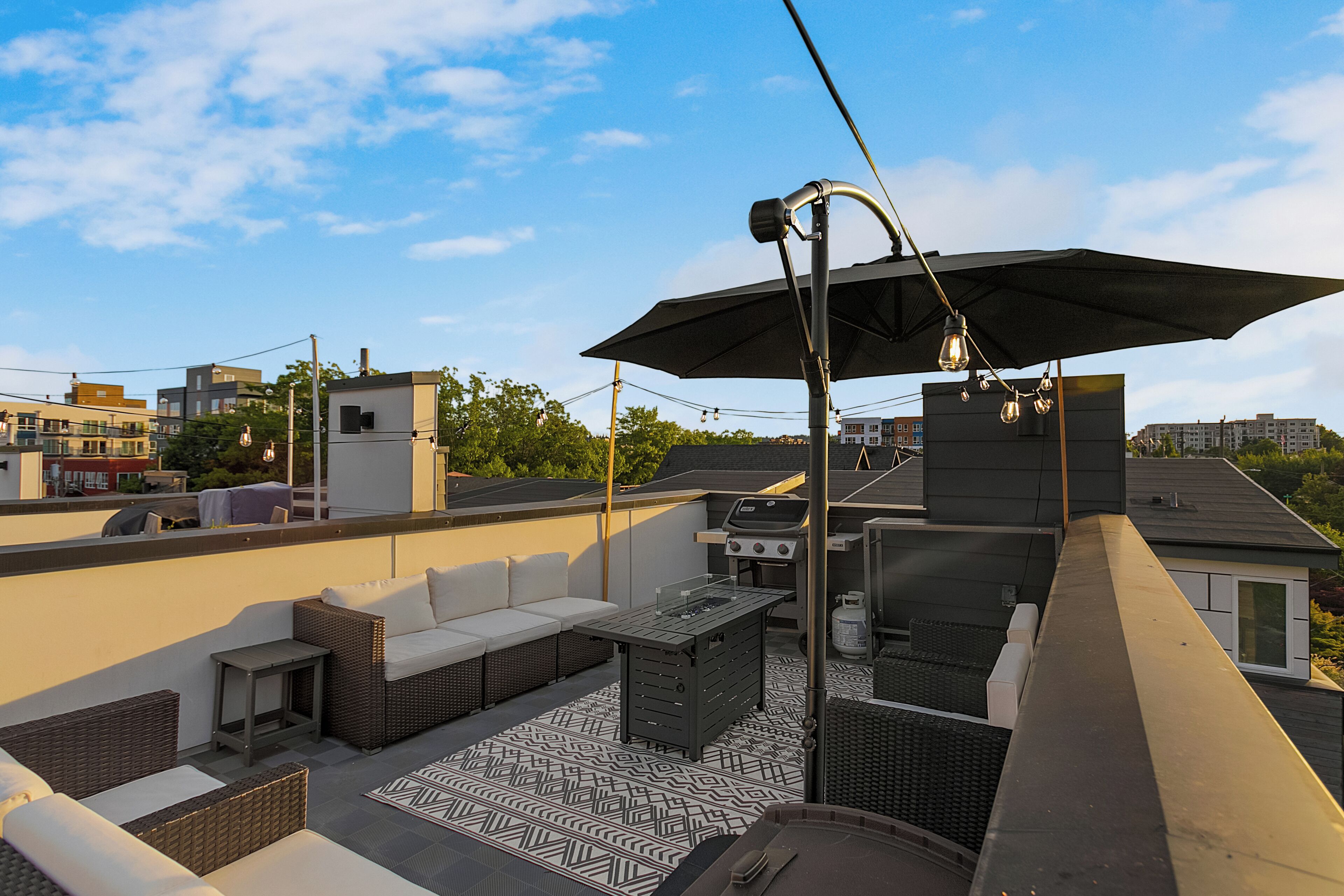 Un patio en la azotea con mobiliario exterior, una parrilla y un suelo estampado.