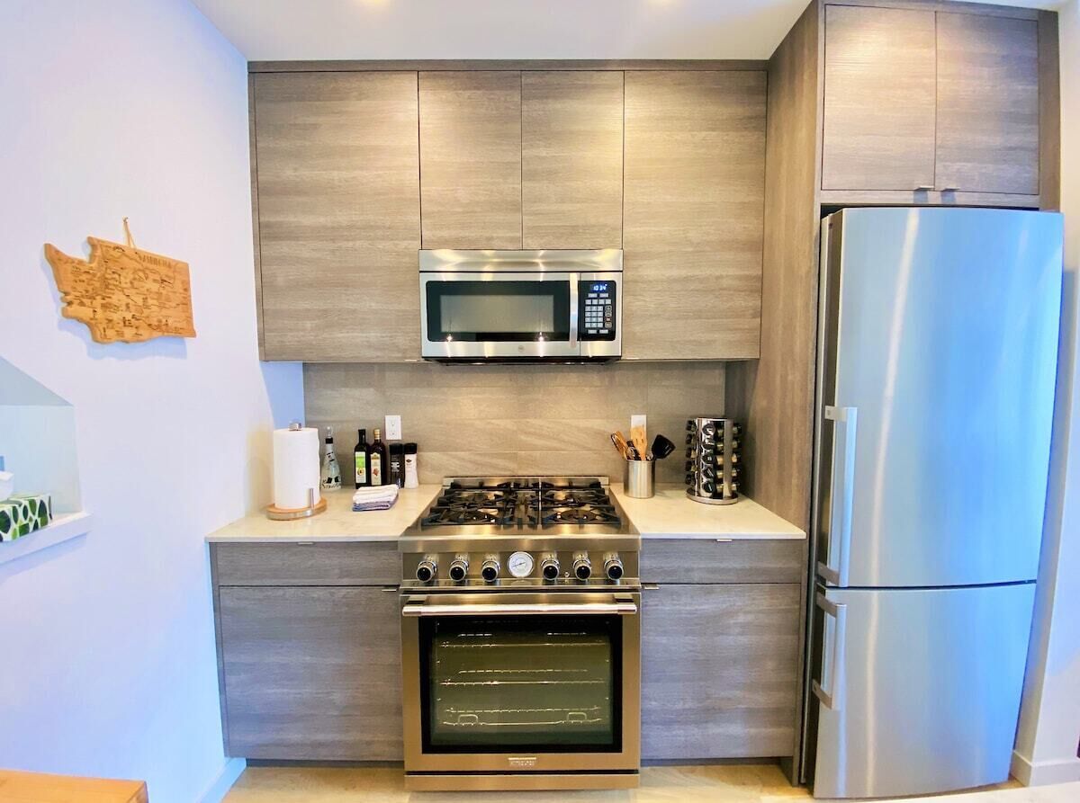 Uma cozinha moderna com fogão, forno, micro-ondas e geladeira de aço inoxidável.