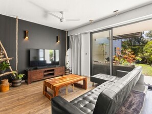 Una sala de estar moderna con televisor de pantalla plana, una mesa de centro de madera y un sofá gris.