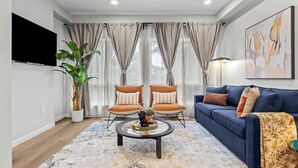 A modern living room with a blue sofa, two armchairs, a coffee table, and a large plant.