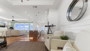 Uma sala de estar moderna com um espelho grande, um telescópio e vista para a cozinha e a sala de jantar.