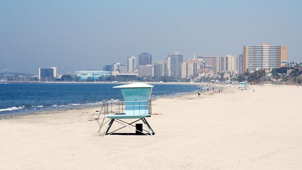 Una torre de salvavidas en la playa, con el horizonte de una ciudad al fondo.
