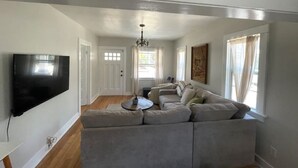 Una sala de estar con un sofá modular, un televisor de pantalla plana y una araña.