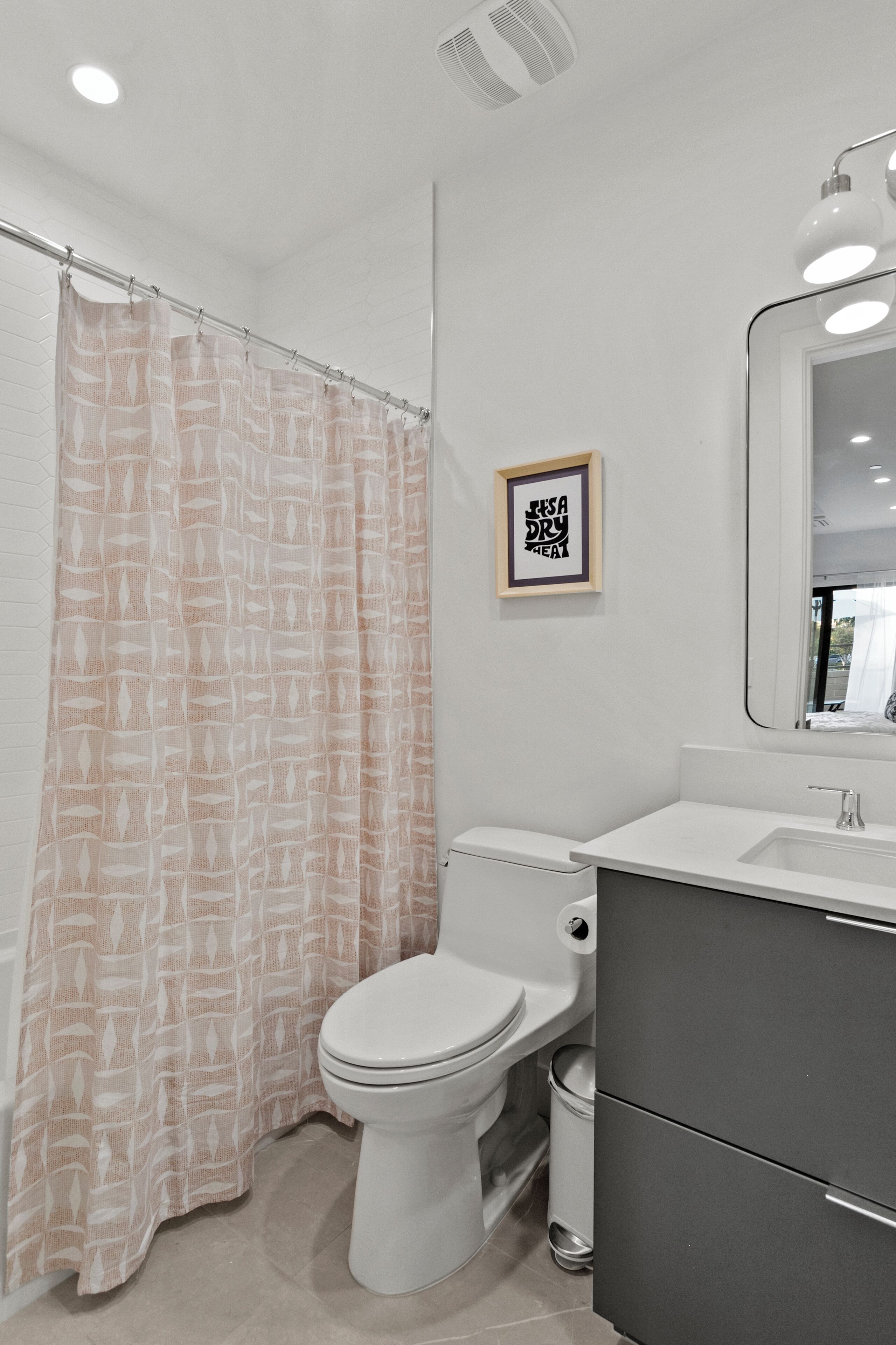 Un baño con inodoro, lavamanos, espejo y cortina de ducha.