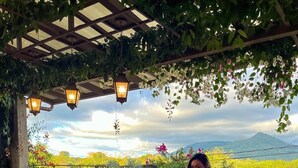 Un espace extérieur abrité, doté d’une table de pique-nique en bois, de lanternes suspendues et d’un sol en pierre.