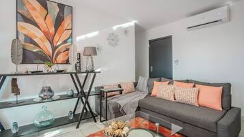 Ein modernes Wohnzimmer mit einem grauen Sofa, einem Glastisch und einem Gemälde an der Wand.