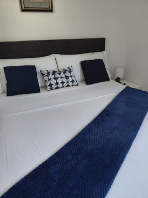 A bed with white bedding, a dark headboard, and three pillows. - 3 bedroom apartment with pool (Marigot)