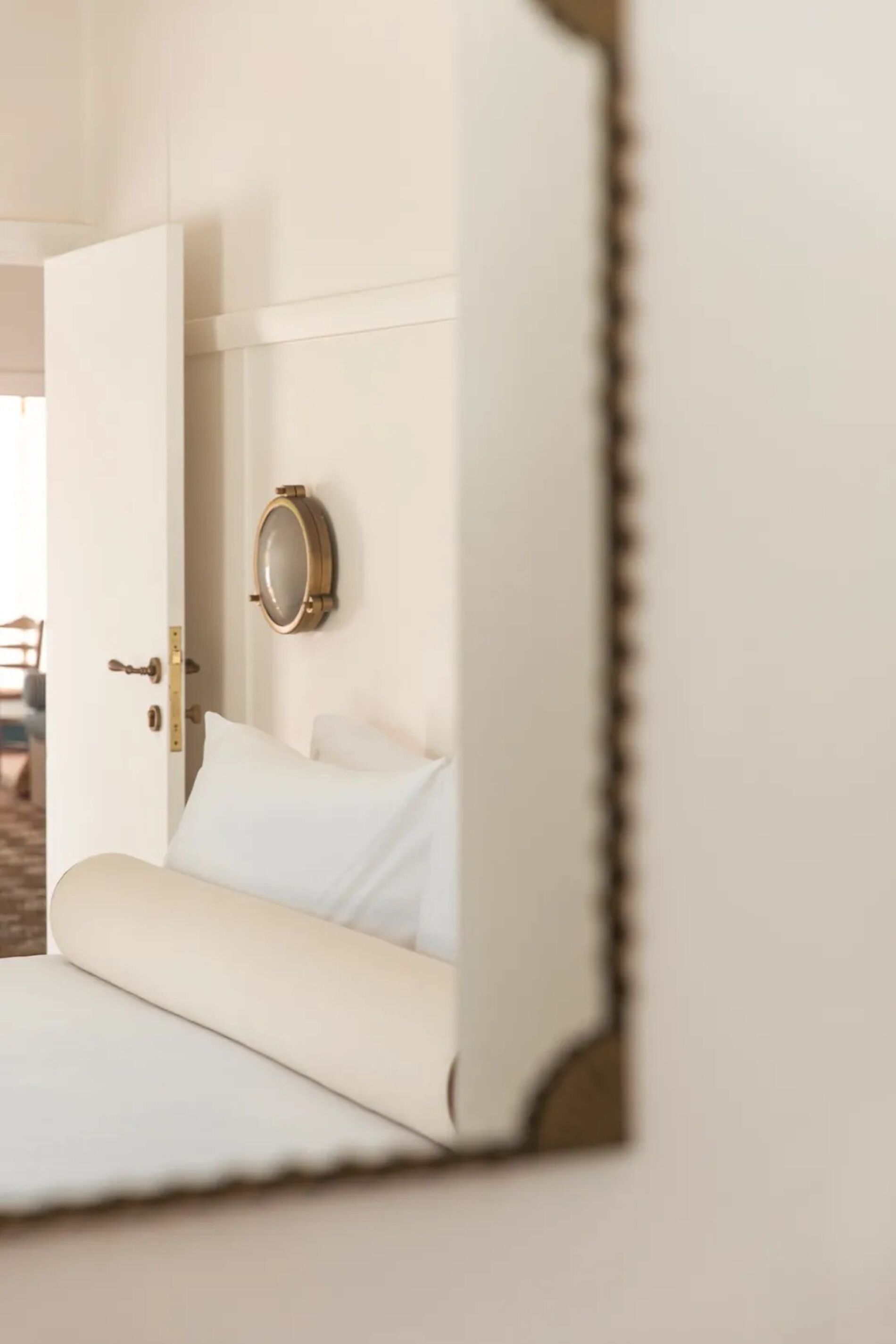 Une chambre à coucher avec un lit, une porte et un miroir fixé au mur.