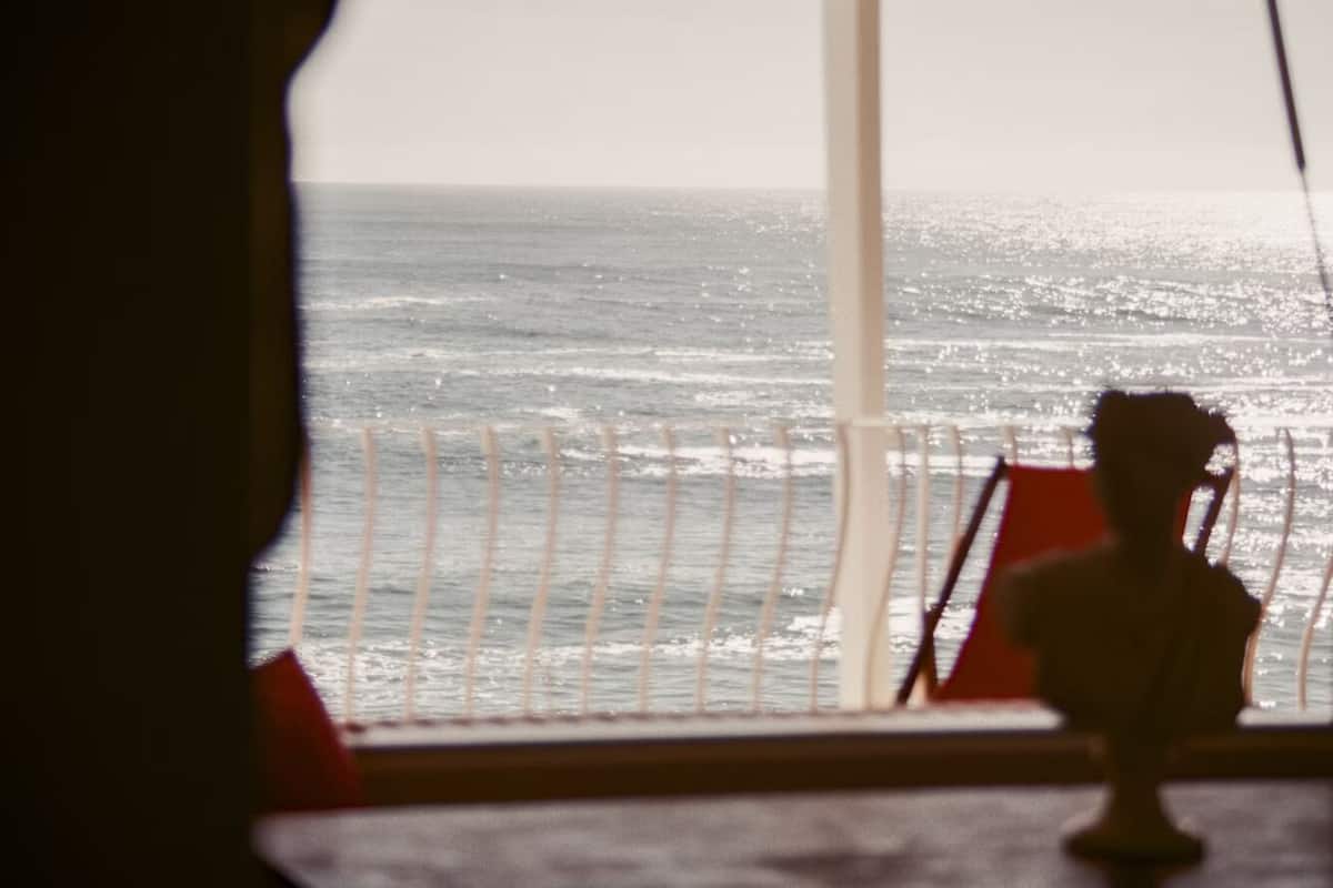Udsigt til havet gennem et vindue med gelænder.
