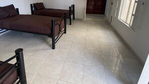 A room with two beds, a wooden wardrobe, and a window. - Hostal Tequila (Tequila)
