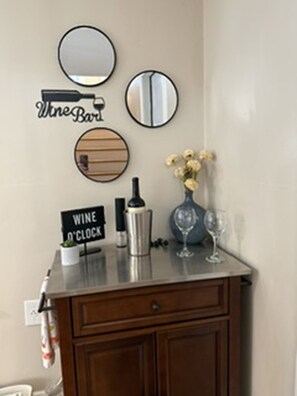 A bar area with a wine bottle, glasses, and a sign indicating 'WINE O'CLOCK'.