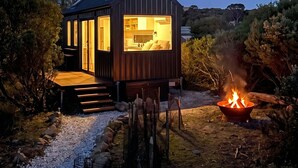 Una casa moderna con cocina a la vista, un hogar y un cielo nocturno despejado.