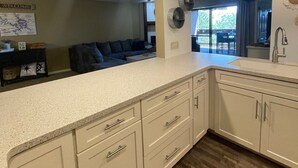 A modern kitchen with white cabinetry, a granite countertop, and a wooden floor. - Beautiful Lake Views w/ Boat Slip! (Osage Township)