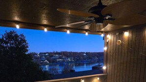 A dining area with a view of a body of water and a town at dusk. - Beautiful Lake Views w/ Boat Slip! (Osage Township)