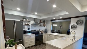 A modern kitchen with a central island, built-in appliances, and a wooden floor. - Beautiful Lake Views w/ Boat Slip! (Osage Township)