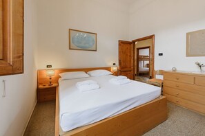 A bedroom with a wooden bed, bedside tables, a nightstand, a dresser, a mirror, and a framed picture on the wall. - La Margherita by MMega (Coverciano)