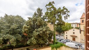 A residential street with trees, parked cars, and buildings with traditional architecture.